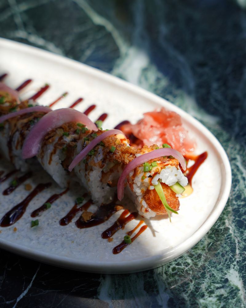 Signature sushi roll finished with pickled onion, crispy topping and dark glaze