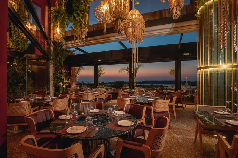 Dining tables set with candles bathed in golden hour light near the New Marina in Rhodes